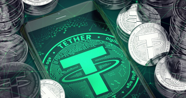 Smartphone with green Tether symbol on-screen among Tether coins. 